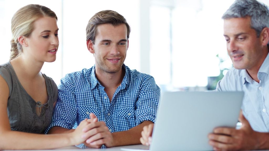 Trois investisseurs discutant de la diversification de portefeuille avec un focus sur les startups à l'aide d'une tablette.