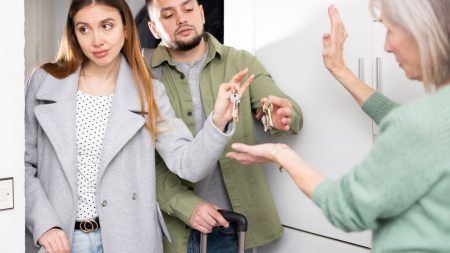 Un couple de locataires rend les clés à une femme âgée sur le pas de la porte.