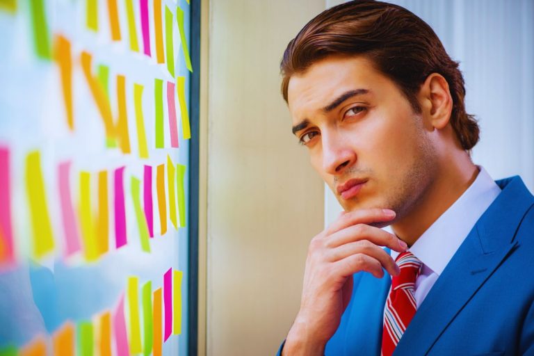 Capitaux propres inférieurs à la moitié du capital social : procédure et formalités Homme en costume analysant des stratégies sur un tableau de notes adhésives.